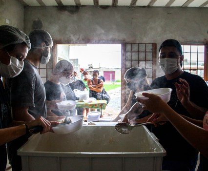 People wearing hairnets and masks, passing out rice