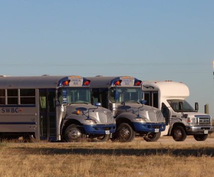 A flare burns behind a fleet of church buses in Midland County, Texas, on Oct. 30, 2021. In West Texas, flares are often located near homes, businesses and other public facilities.