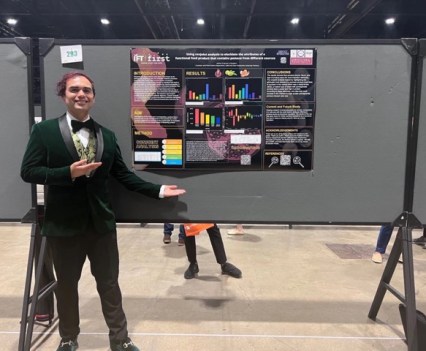 A person in a suit standing next to a poster presentation