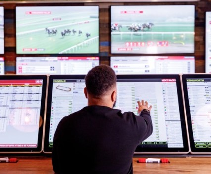 A Ladbrokes customer interacting with a Ladbrokes betting terminal to assess the racing form.
