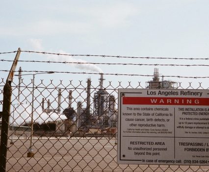 A warning sign on a barbed wire fence outside of a refinery