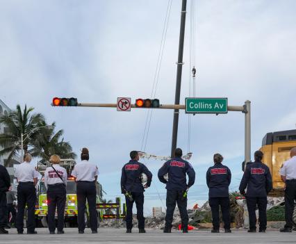 A group of emergency response personnel standing on the street near Surfside condo