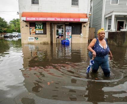 In downtown Charleston, Tonya O’Neal wades through floodwaters following a heavy rain to get back home after leaving Green’s Grocery on Bogard Street on June 13, 2021.