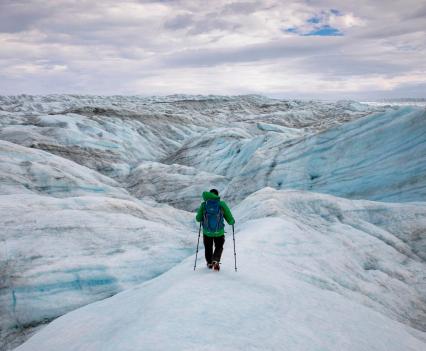 Adam Lyberth maneuvers through blue-and-white hills of ice and snow on the Greenland ice sheet on Aug. 13, 2021. An Inuit shaman, he says he’s walked on the ice more than 3,000 times, and that it changes every day.