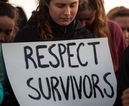 A young person holding a sign that says respect survivors