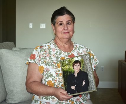 A woman holding a photograph of her deceased son