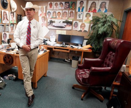 A Texas Ranger standing in his office, the walls covered in police sketches