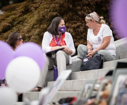 Three women talk in between purple and white balloons