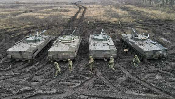 Russian service members walk past BMP-3 infantry fighting vehicles during tactical combat exercises in the Rostov region, Russia, Dec. 10, 2021.