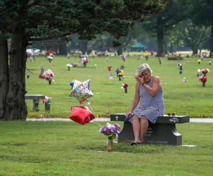 Michele Crockett, mother of Max Gilpin, visits at the grave of her son. It would have been Max Gilpin's 26th birthday, and she brought balloons as she does every year. He died after becoming overheated at football practice at Pleasure Ridge Park High School in 2008. July 19, 2019