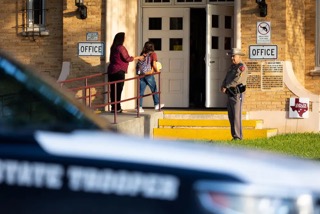 Children arrive to Flores Middle School for the first day of classes in Uvalde, while a DPS officer watches over.
