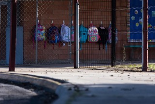 Backpacks hang outside behind an 8-foot-tall fence at Dalton Elementary School, one of the schools where Robb Elementary students were redirected for the new school year.