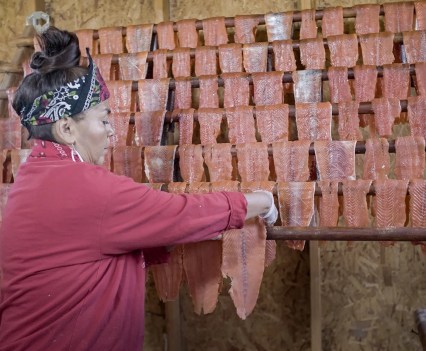 A member of the Confederated Tribes of Warm Springs prepares wind-dried salmon the traditional way, inside a drying shack, in September 2021. After she removes the heads and bones, the salmon is sliced into strips, salted and hung to dry for several days.