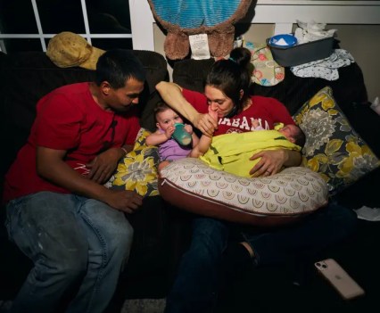 Two adults and a young child sit on a couch together