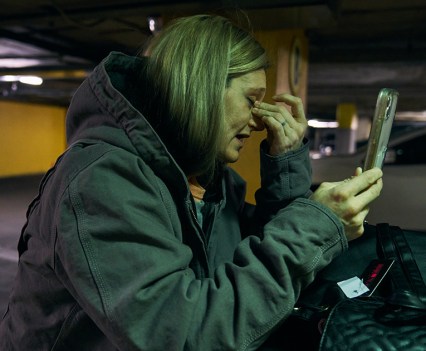 Crying woman holding a cell phone, outside at night