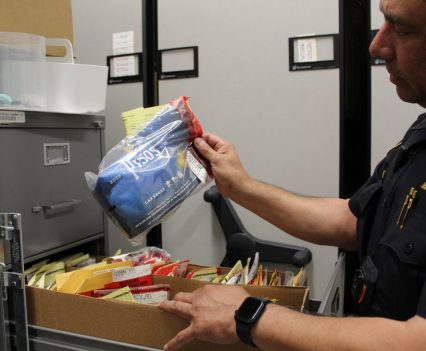 Sgt. Javier Hernandez holds a Pisos bag, one of many items in the departments evidence locker containing confiscated marijuana. Pisos is a dispensary just blocks from campus. Photo by Violet Jira.