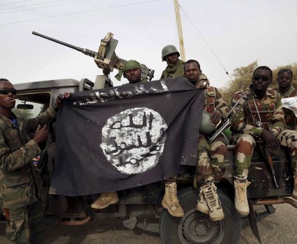 Nigerian soldiers hold a Boko Haram flag seized in the retaken town of Damasak in March 2015. That month, shortly before a presidential election, the army said it had secured most of the northeast – one of many premature declarations of victory. REUTERS/File photo