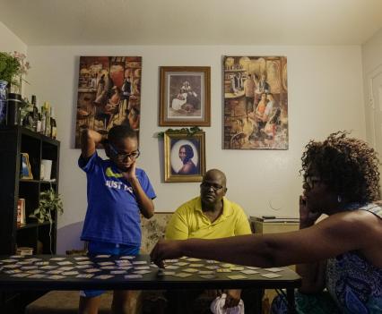 Tressie King, right, plays a matching card game with her husband, Jamel, and their adoptive son at the family’s home in Chandler, Arizona.