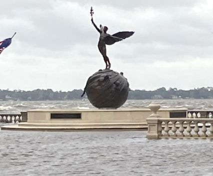 A statue of an angel standing on a globe is surrounded by flood water