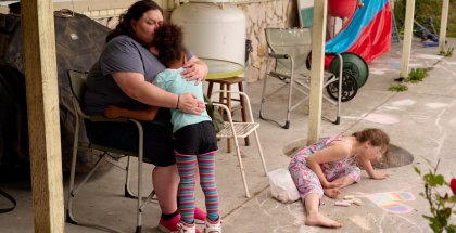 Ashley Traister, left, hugs her daughter while her niece plays with chalk in the backyard of Traister’s sister’s home in Port Ludlow, Washington, in June. MERON MENGHISTAB FOR THE MARSHALL PROJECT