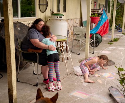Ashley Traister, left, hugs her daughter while her niece plays with chalk in the backyard of Traister’s sister’s home in Port Ludlow, Washington, in June. MERON MENGHISTAB FOR THE MARSHALL PROJECT