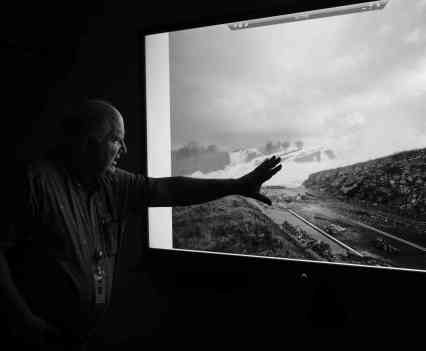 Wes Monier, a hydrologist, with a 1997 photo of water rushing through the New Don Pedro Reservoir spillway.