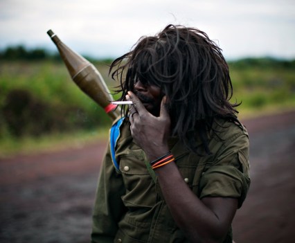 A Congolese government soldier wearing a wig smokes by the roadside near the front line, north of Goma in eastern Congo in this November 11, 2008. More than five million people have died, most from lack of access to food or basic health, during a decade of fighting and upheaval in Congo, according to aid agencies. This makes Congo's enduring conflict the deadliest since World War Two.