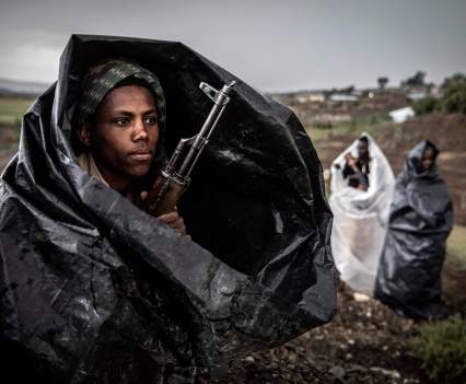 A fighter from the Tigray Defence Forces uses a plastic bag to shelter from a hail storm while guarding a camp holding hundreds of Ethiopian army prisoners of war in the mountains southwest of the regional capital Mekelle in Ethiopia's northern Tigray region, on June 29, 2021