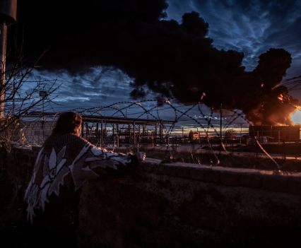 A woman watches a burning oil depot that local residents said had been by a Russian mortar barrage from across the Dnipro River in the southern Ukrainian city of Kherson, November 19, 2022.