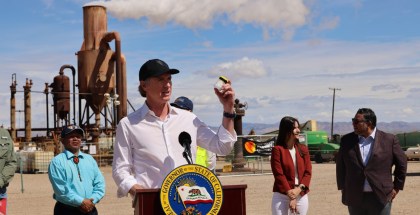 Photo of a politician speaking from behind a podium on the site of an industrial plant