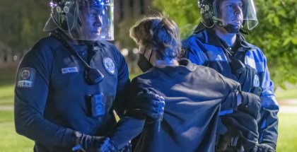 Photo of two police officers holding a masked man at a protest