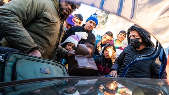 Photo of group led by an African American man donating clothes and shoes to asylum seekers amid the cold temperatures outside the Chicago Police Department’s 2nd District station in Fuller Park