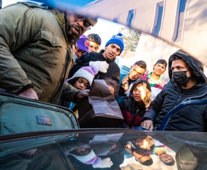 Photo of group led by an African American man donating clothes and shoes to asylum seekers amid the cold temperatures outside the Chicago Police Department’s 2nd District station in Fuller Park