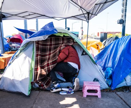 Photo of a person going into a tent as asylum seekers huddle in tents outside the Fuller Park police station