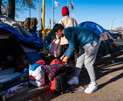 Photo of a man bending over a backup in front of a tent