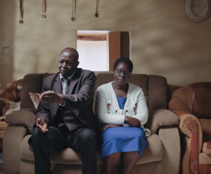 Photo of black man and woman seated next to each other on a couch