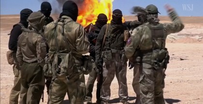 Photo of a group of military men with black masks on in front of a fire