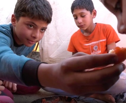 Photo of a group of boys, one of them giving a piece of food to another