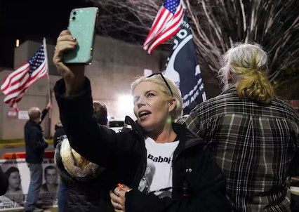 Photo of a woman taking a photo with an American flag in the background