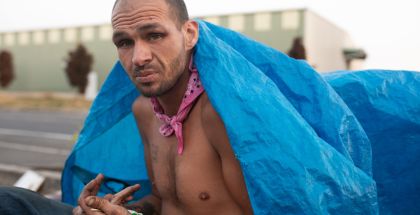 Photo of a man without a shirt on covering his back with a blue tarp