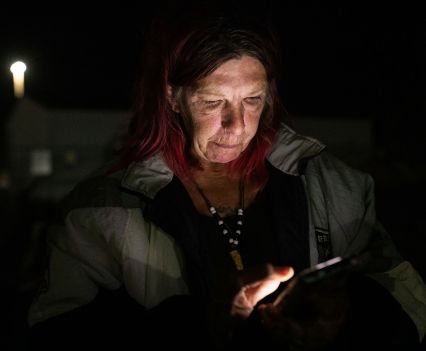 Woman looking at her lit up phone screen in the dark