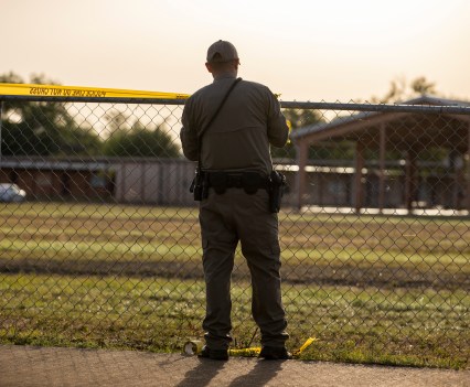 Man, presumably police officer, putting police tape around a fence