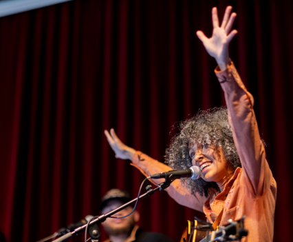 Woman with her arms up on stage in front of microphone