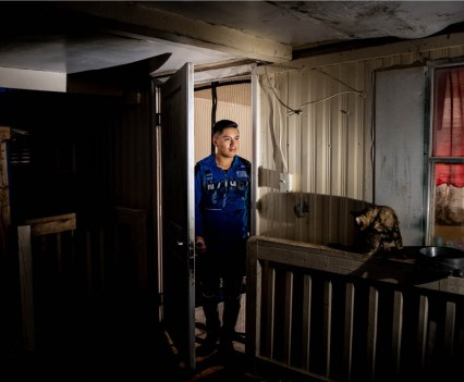 Photo of young man walking into a dark room with a cat near the window