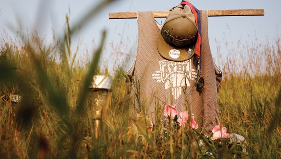 Cross memorial with a hat hanging on it