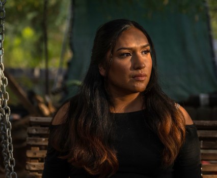 A woman sits outside at night in dim lighting