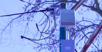 An electronic device is attached to a pole and surrounded by wires