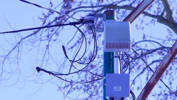 An electronic device is attached to a pole and surrounded by wires