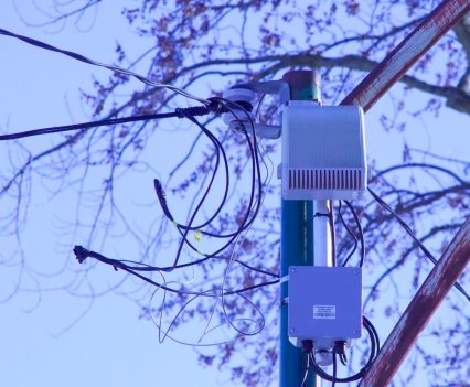 An electronic device is attached to a pole and surrounded by wires