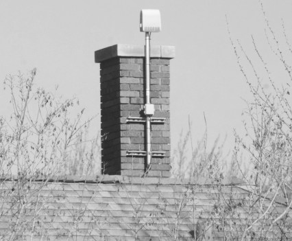 A ShotSpotter sensor attached to a brick chimney